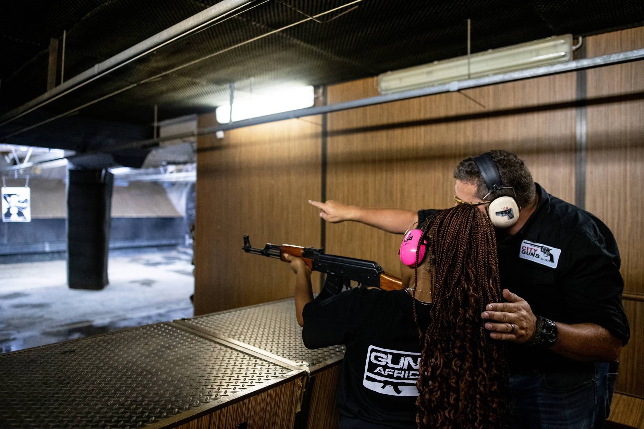 Gun Fun's FAQ: Woman being assisted with a manually operated shot gun.
