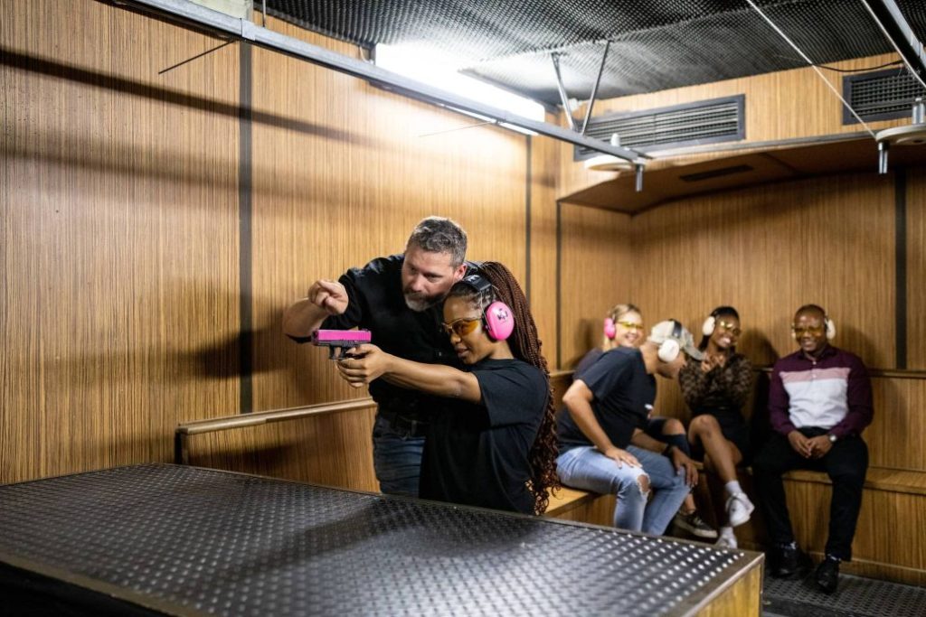 Woman learning to shoot with a pink handgun at Gun Fun, Cape Town" Women's Day 2-for-1 special 2024